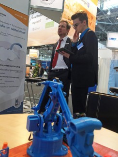 Tim Möckel erklärt Christoph Neuberg, Geschäftsführer Industrie/Außenwirtschaft der IHK Chemnitz, spannende CBS-Lösungen über einen Monitor. Foto: CBS Information Technologies AG